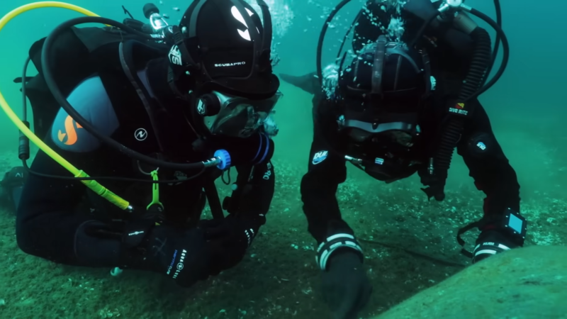 Two divers examining the stone structure underwater in Lake Michigan