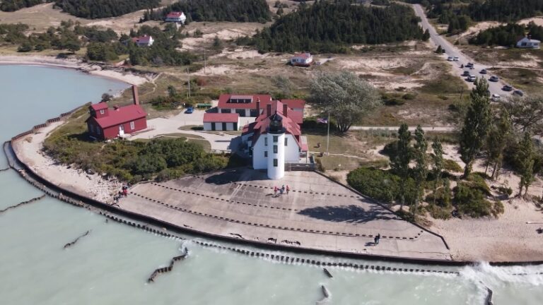Lighthouses of Michigan with red roofs sit by the lake on a wide, curved shoreline